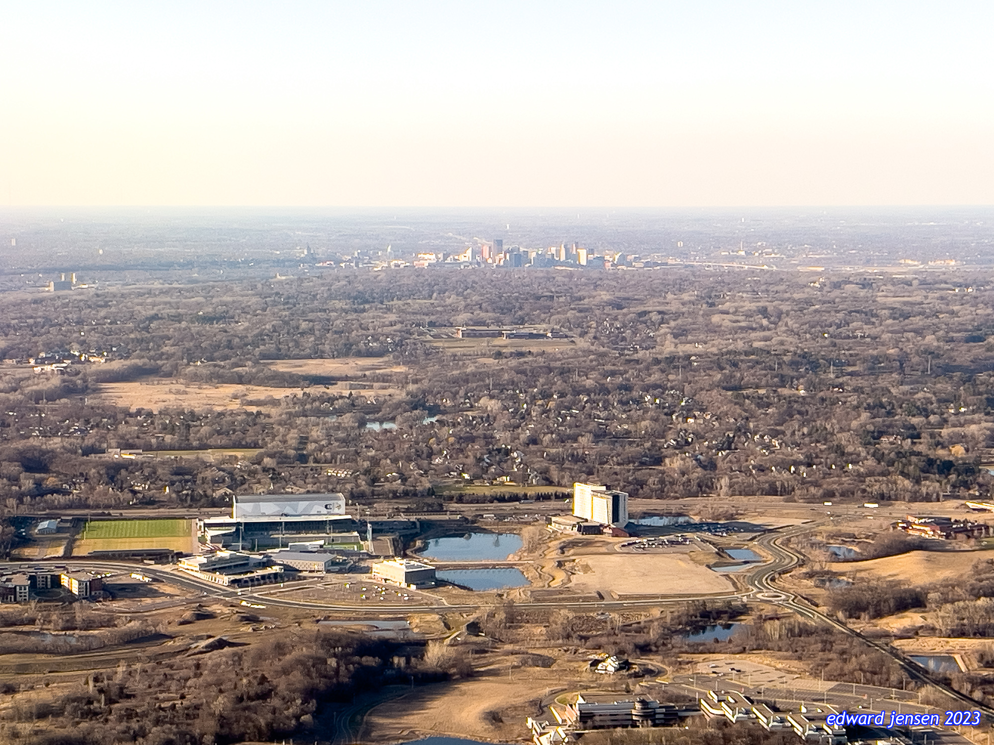 Aerial view of a the downtown Saint Paul city landscape with a stadium complex in the foreground and downtown skyline visible in the distance. Surrounding areas show residential neighborhoods, parks, and water features.