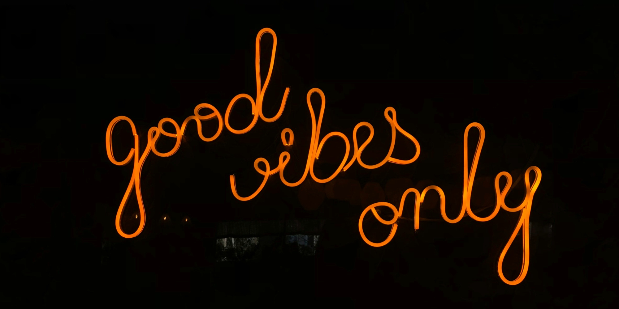 Neon sign with orange cursive text against a black background reading 