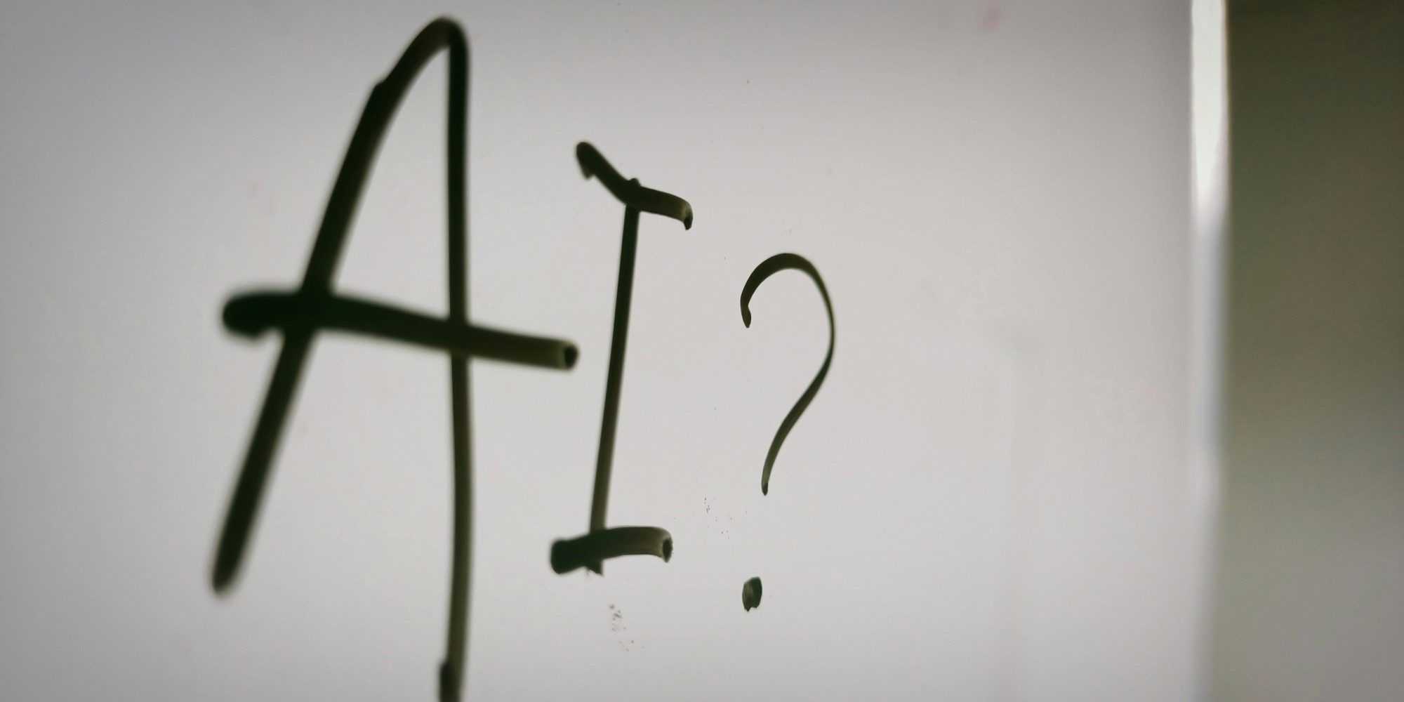 Handwritten text on a whiteboard or light grey surface reading \